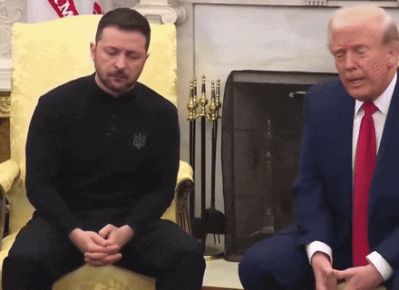 a man in a black shirt with the word ukraine on it sits next to a man in a suit