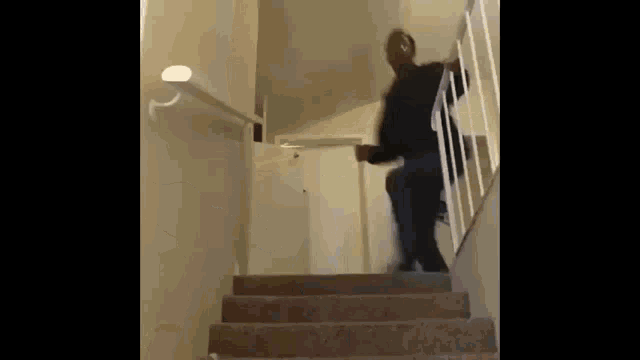 a man is walking down a set of stairs in a room .