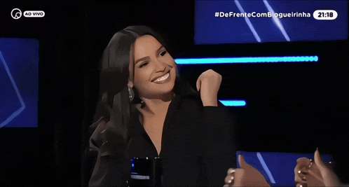 a woman is smiling in front of a screen that says 20:18