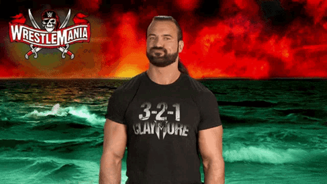 a man in a wrestlemania shirt stands in front of a ocean