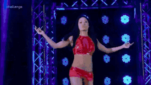 a woman in a red top and shorts is dancing in front of a sign that says challenge on it
