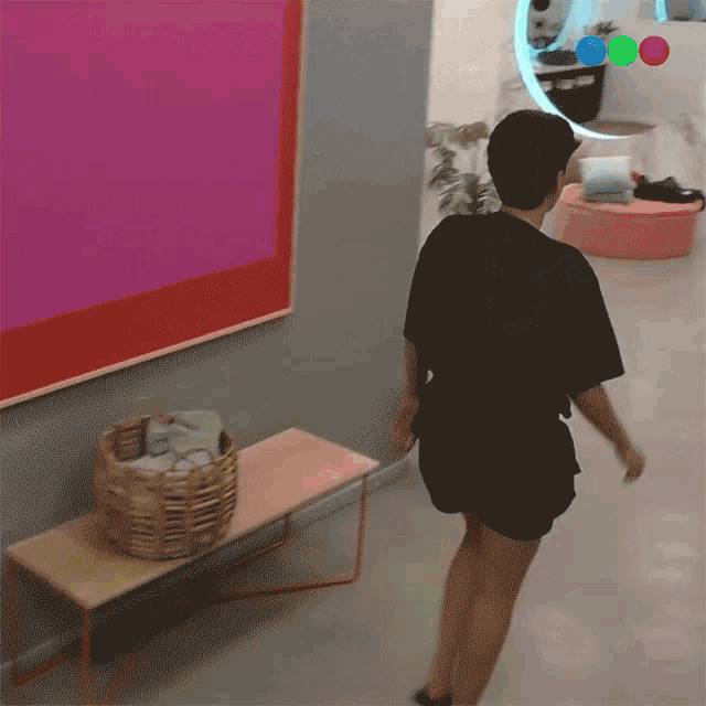 a person in a black shirt is walking in front of a painting