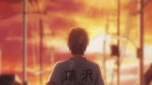 a man with chinese writing on his shirt is walking in front of a sunset