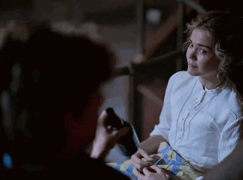 a woman in a white shirt is sitting next to a man in a blue and yellow plaid skirt .