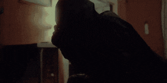 a man is laying on a bed in a dark room with his head down .