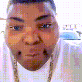 a close up of a man 's face with a white shirt and gold chain around his neck