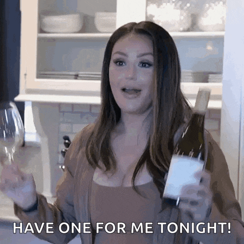 a woman is holding a bottle of wine and a glass .