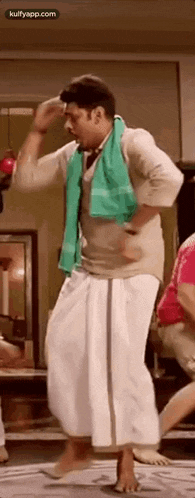a man wearing a green towel around his neck is dancing on a floor .