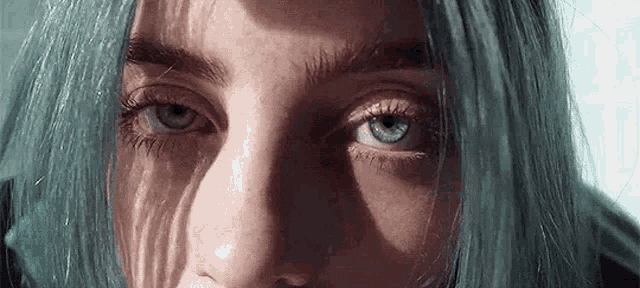 a close up of billie eilish 's face with blue hair .