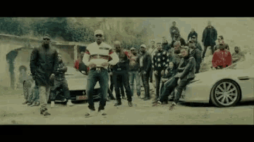 a group of men are posing for a picture in front of a silver car