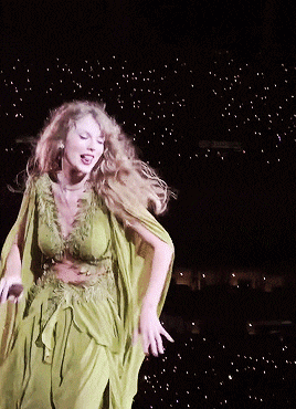 a woman in a green dress dancing on a stage