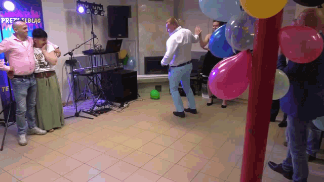 a group of people are dancing in a room with balloons and a sign that says " przeglad " on it