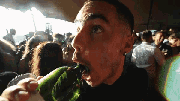 a man drinking from a green bottle with his mouth wide open