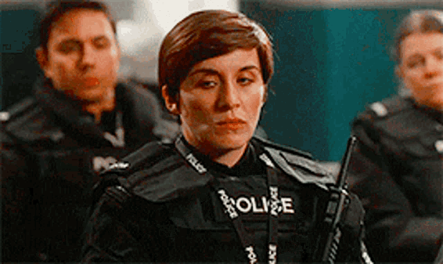 a woman in a police uniform is holding a walkie talkie and looking at the camera .