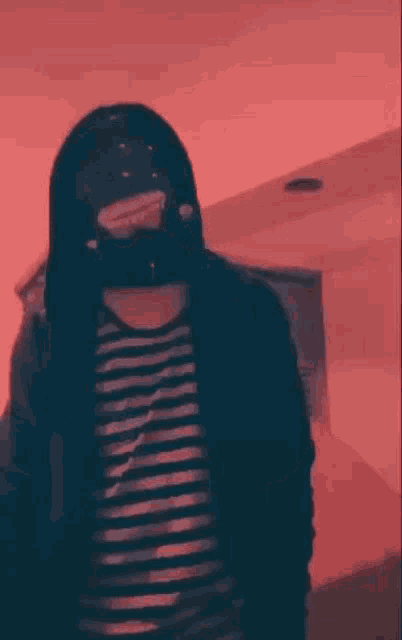a person wearing a mask and a striped shirt is giving a peace sign .