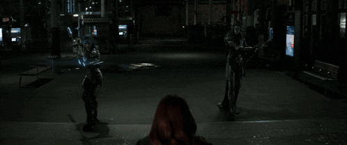 a woman with red hair is standing in a dark room looking out a window