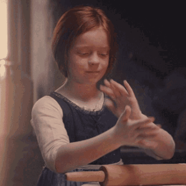 a young girl is rolling dough with a rolling pin