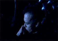 a man in a black turtleneck is sitting in a chair with his finger pointing up
