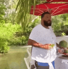 a man with a beard is holding a drink under an umbrella