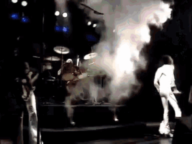 a group of people playing instruments on a stage with smoke coming out of the drums
