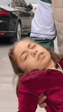 a girl is laying on the ground with her eyes closed and a man is holding her .