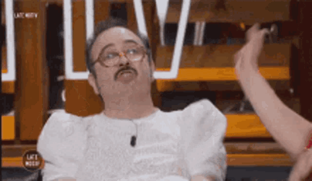a man with glasses and a mustache is wearing a white dress with puffed sleeves