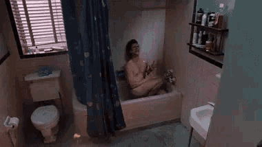 a man is sitting in a bathtub in a bathroom with a toilet and sink .