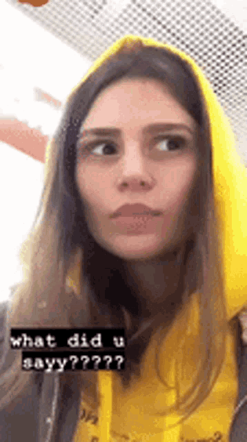 a woman wearing a yellow hoodie is making a funny face
