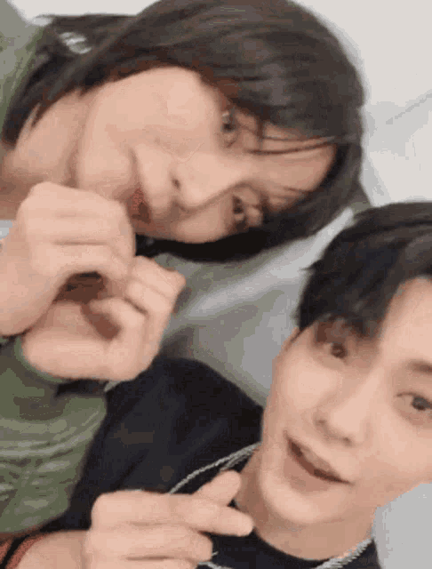 two young men are making a heart with their fingers