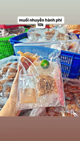 a person is holding a plastic bag of food with a lime in it .