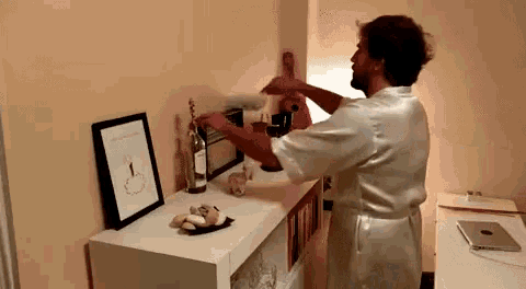 a man in a white robe is standing in front of a shelf with a picture of a penis on it