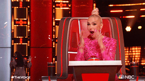 a woman in a pink dress is sitting in a chair with a nbc logo in the corner