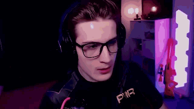 a man wearing glasses and headphones with the word pwr on his shirt