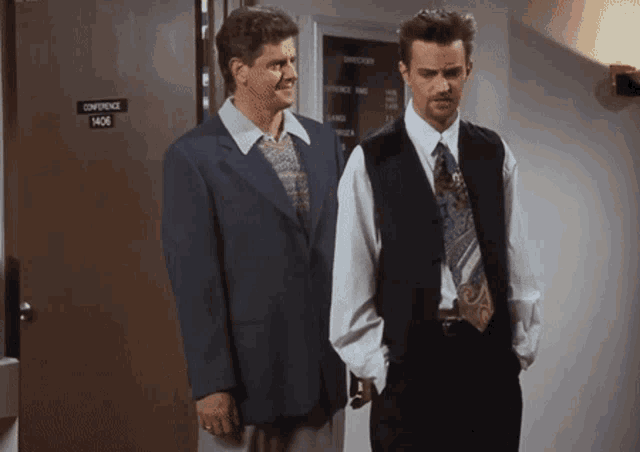 two men stand in front of a conference room door