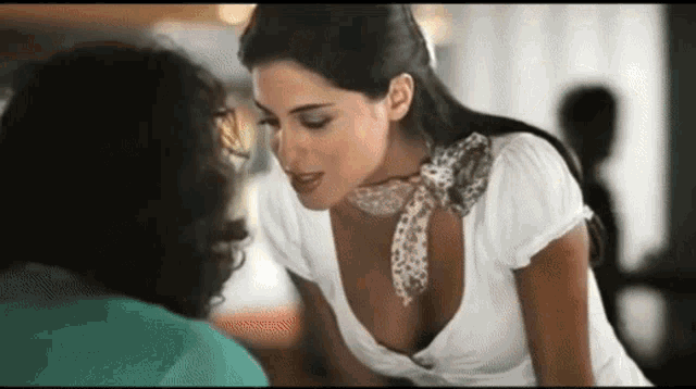 a woman in a white top with a scarf around her neck is talking to a man