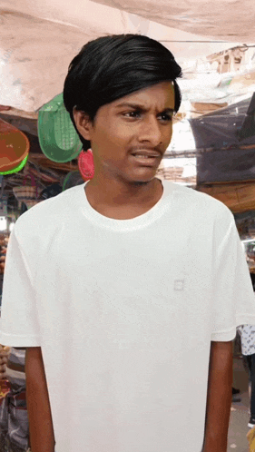 a young man wearing a white t-shirt with a small square on the front