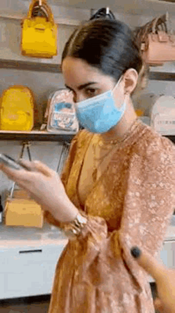 a woman wearing a face mask is looking at her cell phone .