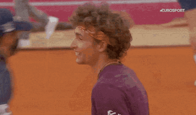 a man with a bandana on his head is smiling in front of a eurosport sign