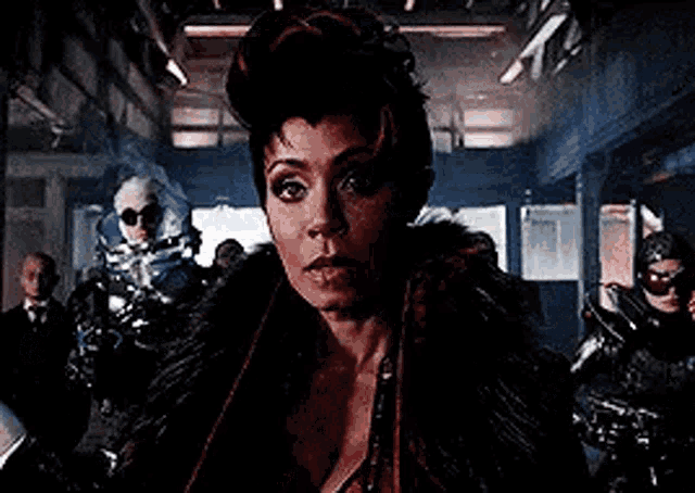 a woman in a fur coat is standing in front of a group of people .