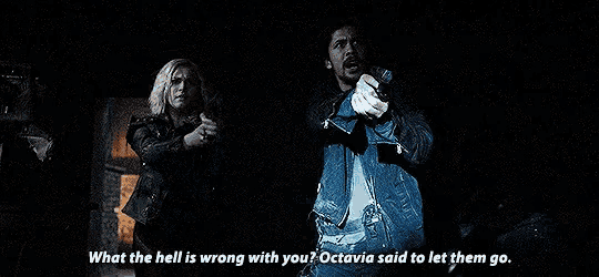 a man and a woman are standing next to each other in a dark room holding guns and a light .