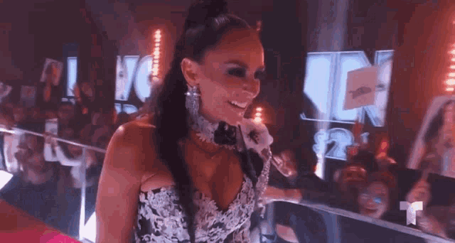 a woman in a very revealing dress is standing in front of a crowd holding a microphone .