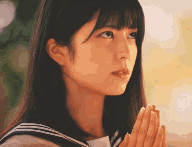 a girl with her hands folded in front of her face