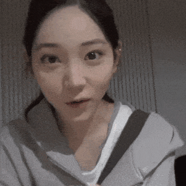 a close up of a woman wearing a gray hoodie