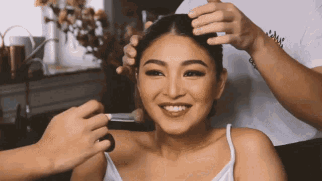 a woman is smiling while getting her hair done by a man wearing a white shirt that says ' astrid '