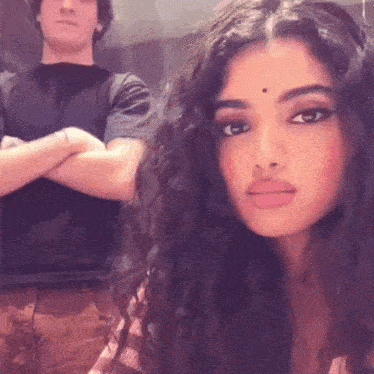 a woman with long curly hair is standing next to a man .