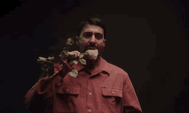 a man in a red shirt is holding a white rose