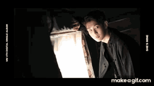 a young man in a black shirt is standing next to a window .