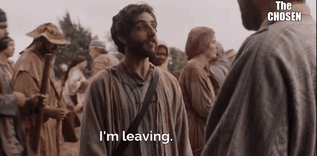 a man with a beard is standing in front of a crowd of people and says i 'm leaving .