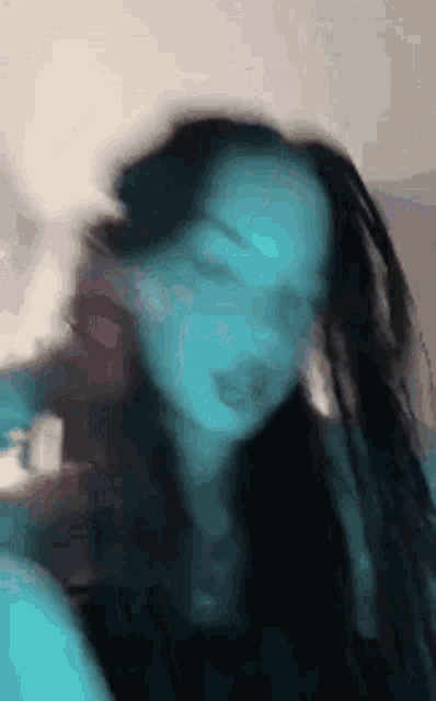 a blurry picture of a woman with long black hair and dreadlocks .