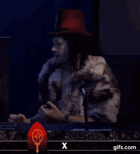 a woman in a top hat is sitting at a table with a microphone and says i 'm done x